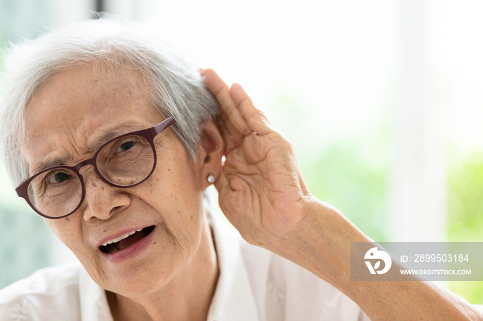 Asian senior woman listening by hand’s up to the ear,having difficulty in hearing,elderly woman hard to hear,wear glasses with hearing impairment,hearing impaired old people