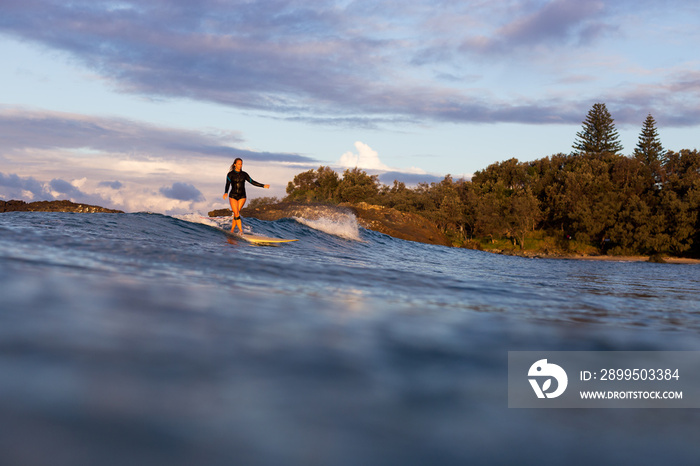 Woman surfing wave at sunset in Australia