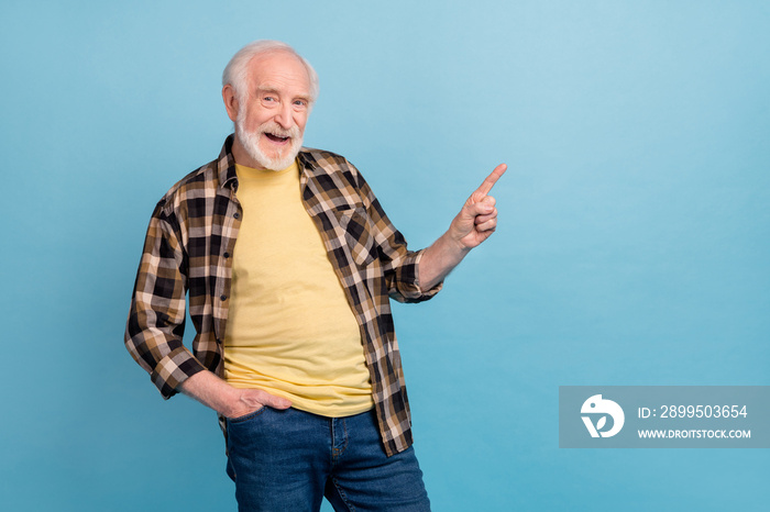 Photo of charming funny man pensioner dressed checkered pointing empty space isolated blue color background