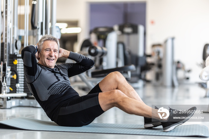 Pensioner male staying fit by making situps inside a gym