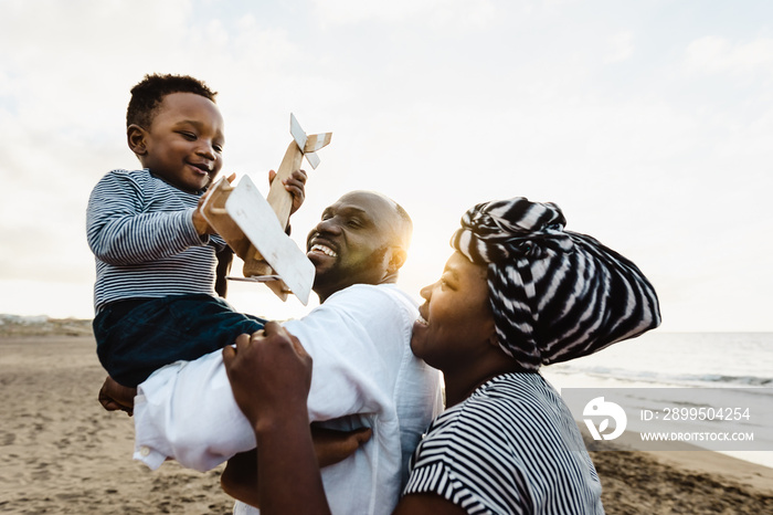 Happy African family having fun on the beach during summer vacation - Parents love and unity concept