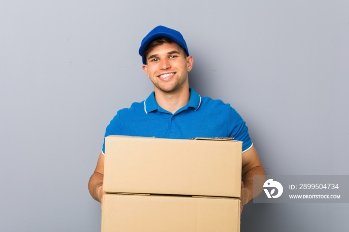 Young man delivering packages happy, smiling and cheerful.