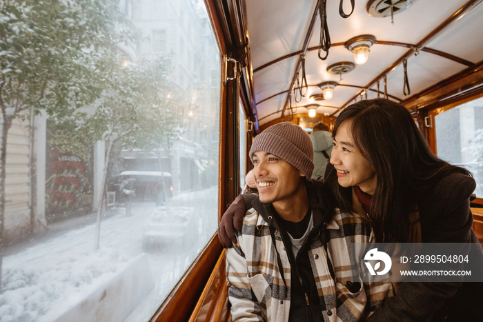 Portrait of young asian man and woman looking at the snow through train window. couple passenger riding classic train during their trip in turkey