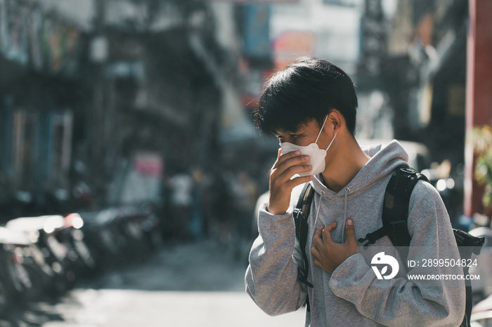 Man wearing N95 Respiratory Protection Mask feels headaches and cough due to air pollution when walking in the market. Air pollution caused health problems. environmental pollution concept.