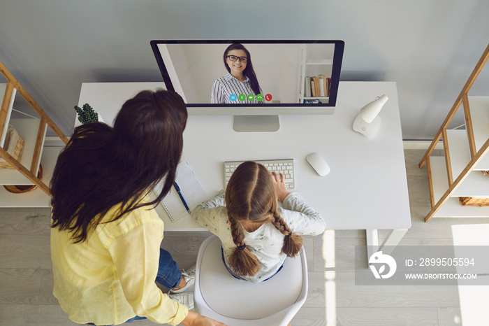 Online learning lessons education school. Mother and daughter are doing online education with a teacher using a laptop sitting at home.