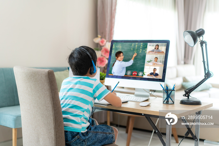 Asian boy student video conference e-learning with teacher and classmates on computer in living room at home. Homeschooling and distance learning ,online ,education and internet..