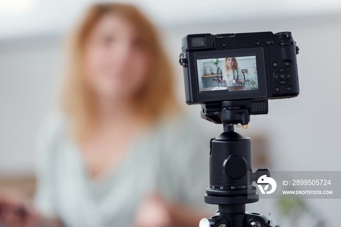 Blurred image of woman blogger at table with florarium. Shooting master class on video camera