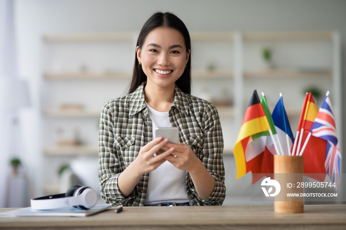 Cheerful asian young lady using smartphone, having English class