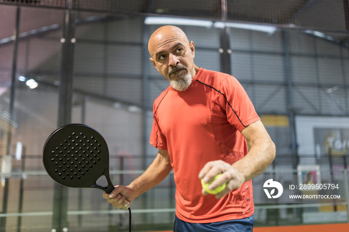 senior man playing paddle tennis in court