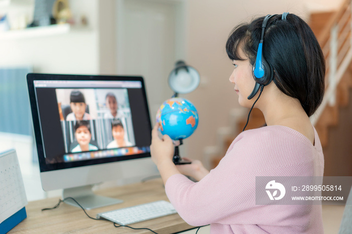 Asian woman teacher teaching geography via video conference e-learning and cheerful elementary school student looking at globe, Homeschooling and distance learning ,online ,education and internet..