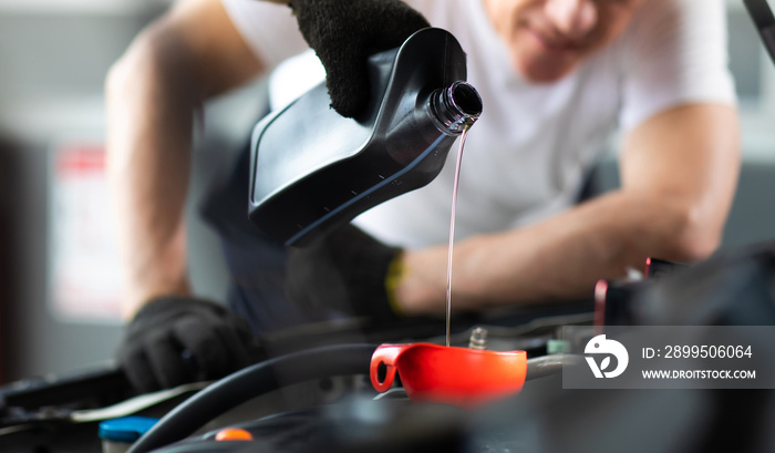 Pouring oil to car engine. Closue up male mechanic hand working  and service in Car Service station