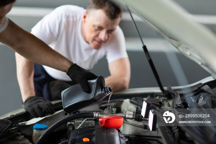 Pouring oil to car engine. Closue up male mechanic hand working  and service in Car Service station