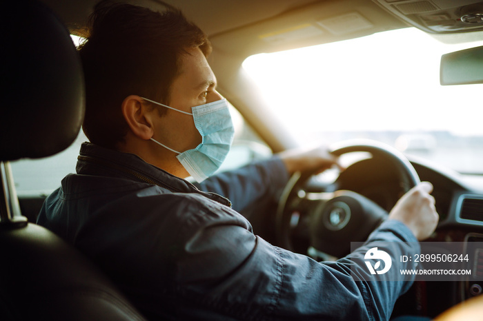 Young man in protective sterile medical mask driving car. The concept of preventing the spread of the epidemic and treating coronavirus, pandemic in quarantine city. Covid -19.