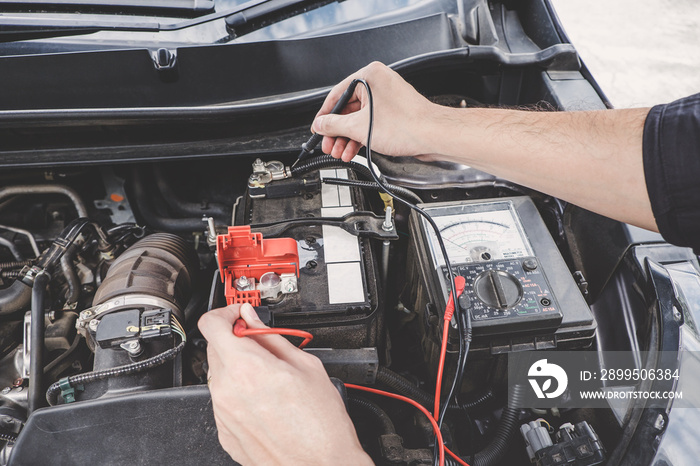 Services car engine machine concept, Automobile mechanic repairman hands checking a car engine automotive workshop with digital multimeter testing battery, car service and maintenance