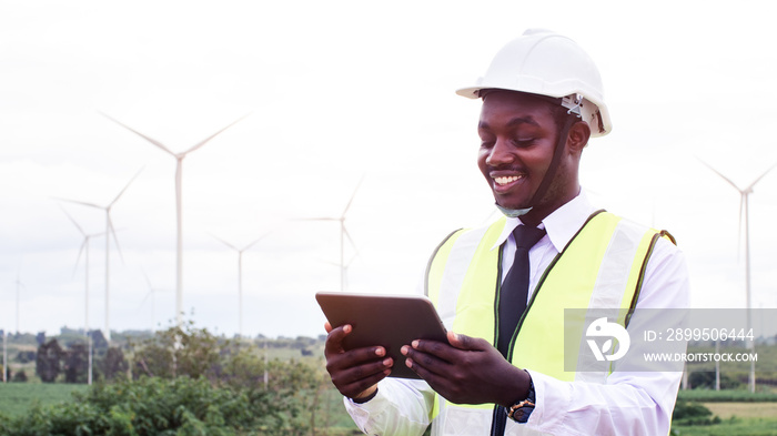 African male engineers working on site with wind turbine propeller and clear blue sky on the background. Alternative energy, environmental friendly for the future. clean energy innovation