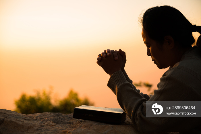 Silhouette of woman kneeling down praying for worship God at sky background. Christians pray to jesus christ for calmness. In morning people got to a quiet place and prayed. copy space.