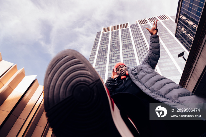 hip hop man walking above the camera lens under skyscrapers - stylish african american dj performing on street