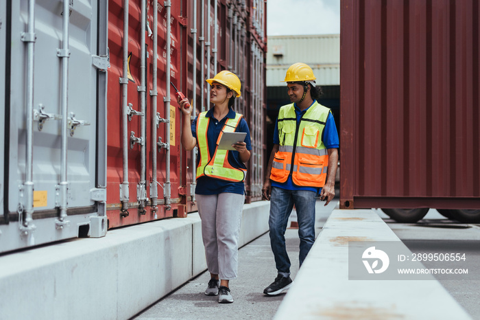 Industrial Engineer checking containers with digital tablet and portable radio in Logistic center. Female manager talking with male workers to working about shipment in Container terminal.