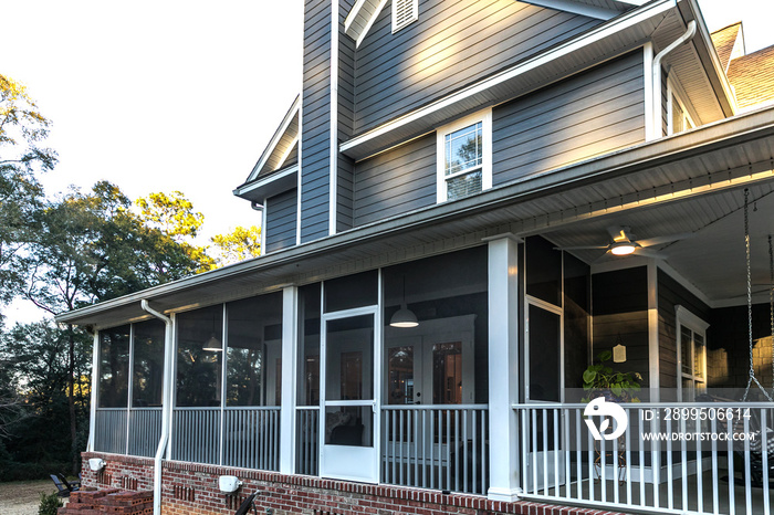 Side view of a large two story blue gray house with wood and vinyl siding