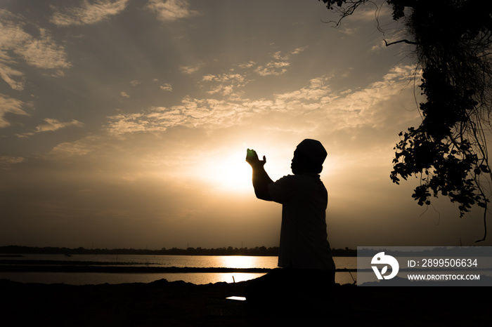 Silhouette Young asian muslim man praying on sunset,Ramadan festival concept