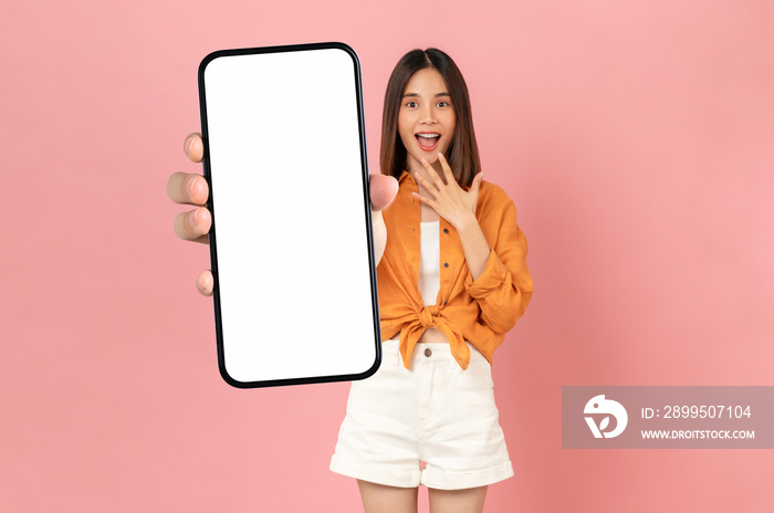 Beautiful Asian woman holding smartphone mockup of blank screen and smiling on pink background.