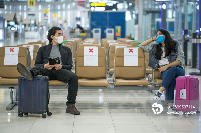 Backpacker travelers Asian women wearing masks covid 19 disease Prevention An sitting, creating a social distancing while waiting check in with smartphone in the airport terminal.