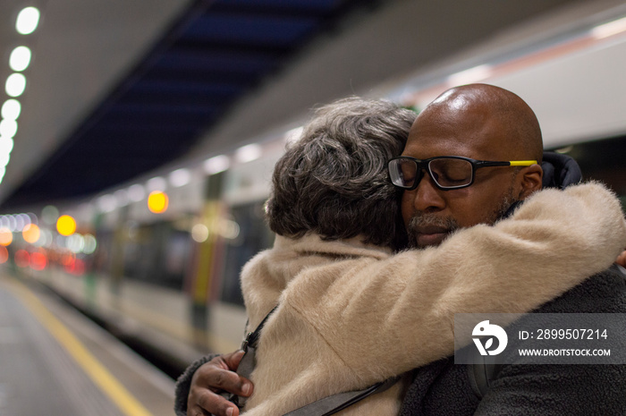 Senior couple embracing at train station