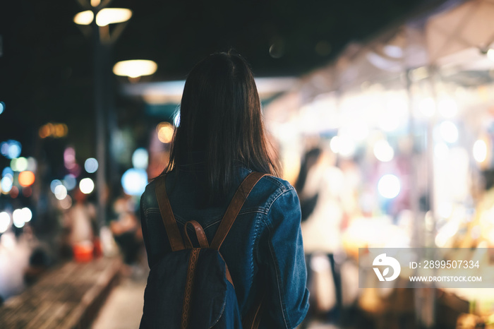 Young traveller woman walking on city street at night.