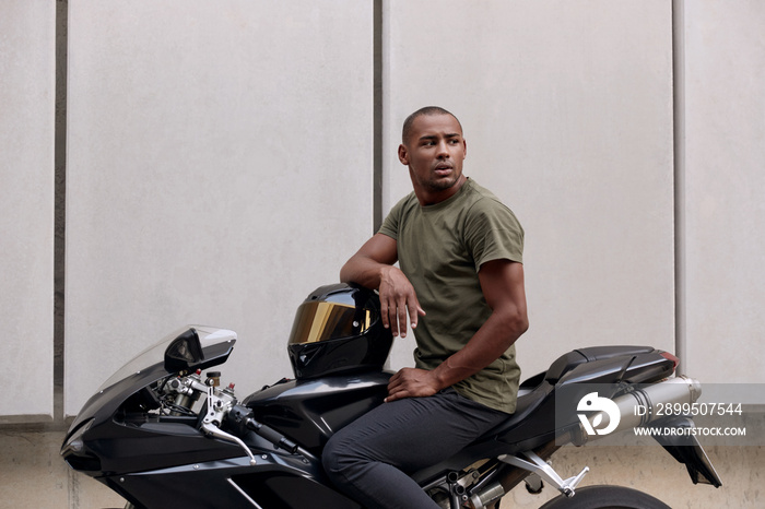 Young black man sitting on sports motorcycle