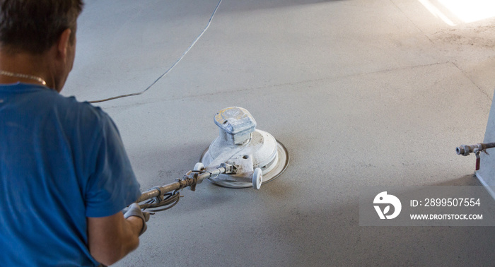 Laborer performing and polishing sand and cement screed floor. Sand and cement floor screed.