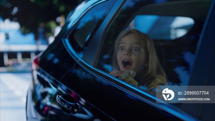 Happy excited cute little girl having fun while riding on a backseat of a car during road trip