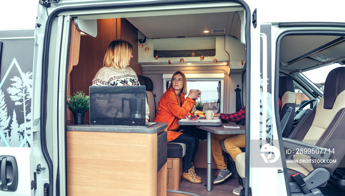 Happy friends having breakfast in a camper van in the morning