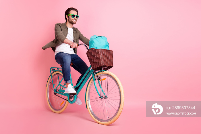 Full length body size view of attractive cheerful guy riding bike traveling rest relax isolated over pink pastel color background