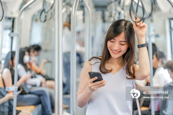 Young Asian woman passenger using social network via smart mobile phone in subway train when traveling in big city,japanese,chinese,Korean lifestyle and daily life, commuter and transportation concept