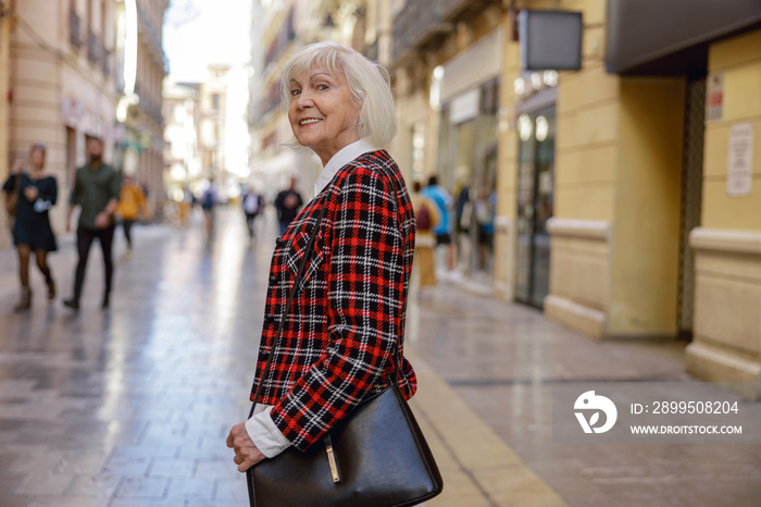 Trendy pensioner female walking outdoors in town