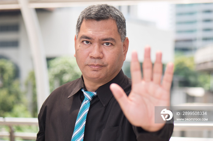 angry business man saying no. portrait of angry, upset asian businessman showing stop, halt hand gesture. 50s old southeast asian man model