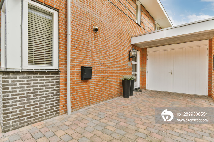 a brick house with an attached garage door and white shutters on the side of the house there is a planter in front