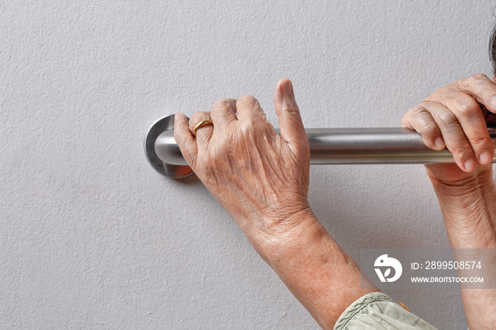 Elderly woman holding on handrail for safety walk steps