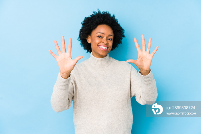 Middle aged african american woman against a blue background isolated showing number ten with hands.