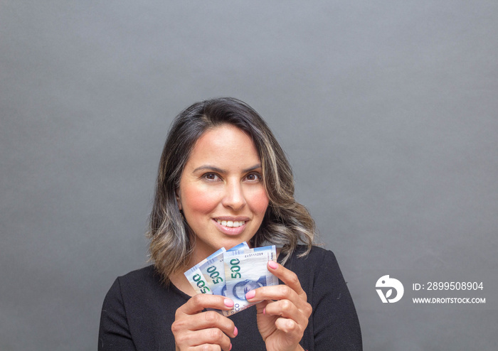 middle aged woman showing 500 mexican pesos bills. economy concept