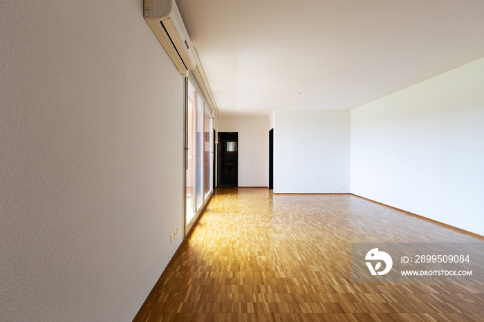 Large empty room with white walls and 70’s parquet