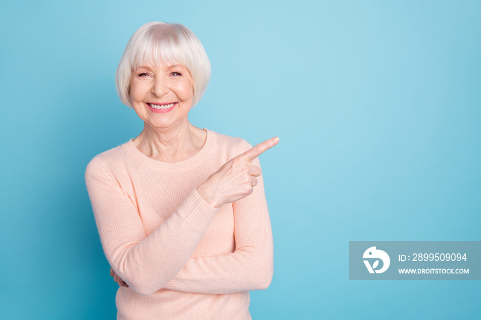 Portrait of lovely lady pointing at copy space having toothy smile isolated over blue background