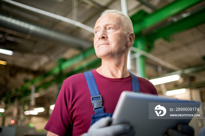 Senior worker with modern gadget thinking of which method of industrial processing to search in the net