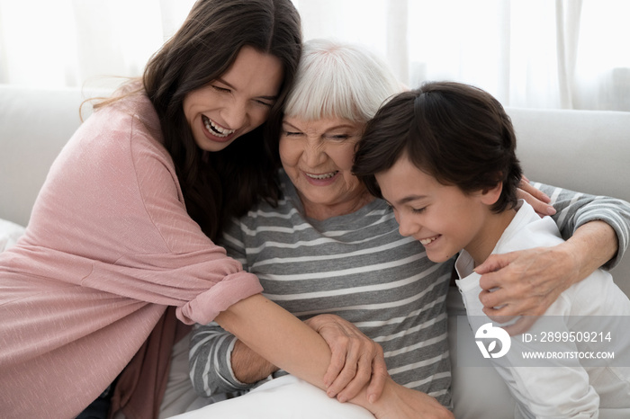 Smiling gray-headed lady being hugged by her family