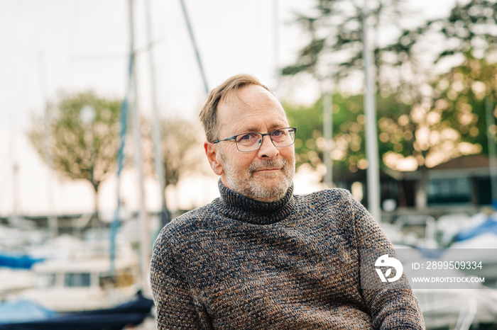 Outdoor portrait of 50 year old man wearing brown pullover and eyeglasses