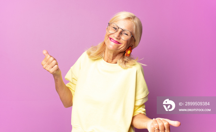 middle age woman smiling, feeling carefree, relaxed and happy, dancing and listening to music, having fun at a party