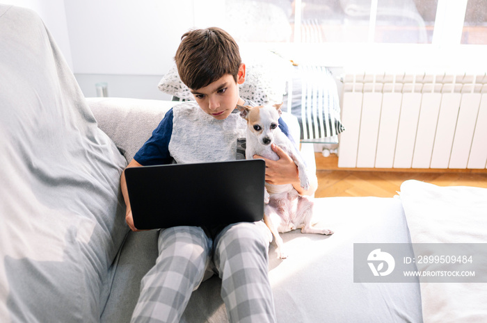 11 year old boy with laptop and dog at home