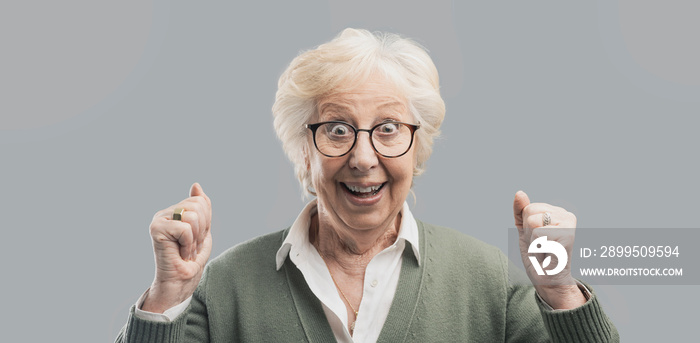 Cheerful senior lady celebrating her victory with raised fists