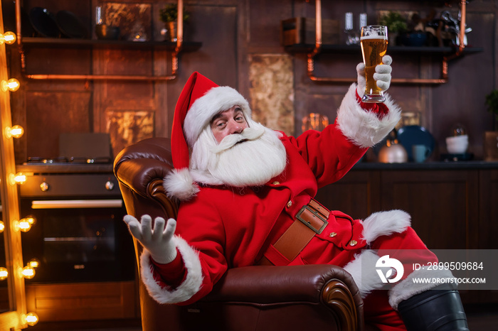 Santa Claus drinks beer while sitting in a leather armchair