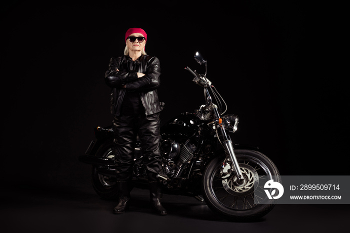 Portrait of her she nice attractive old grey-haired lady hipster rocker traveler chopper rider wearing leather clothes look outfit folded arms isolated black color background